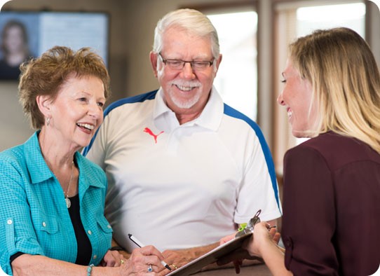 a couple of smiling seniors holding a clipboard